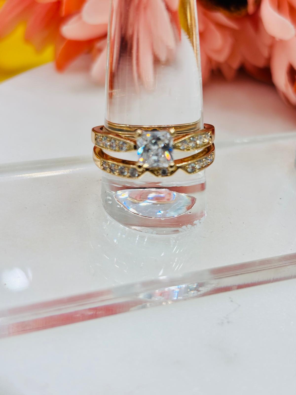 Gold ring with a diamond on a clear stand against a blurred floral background